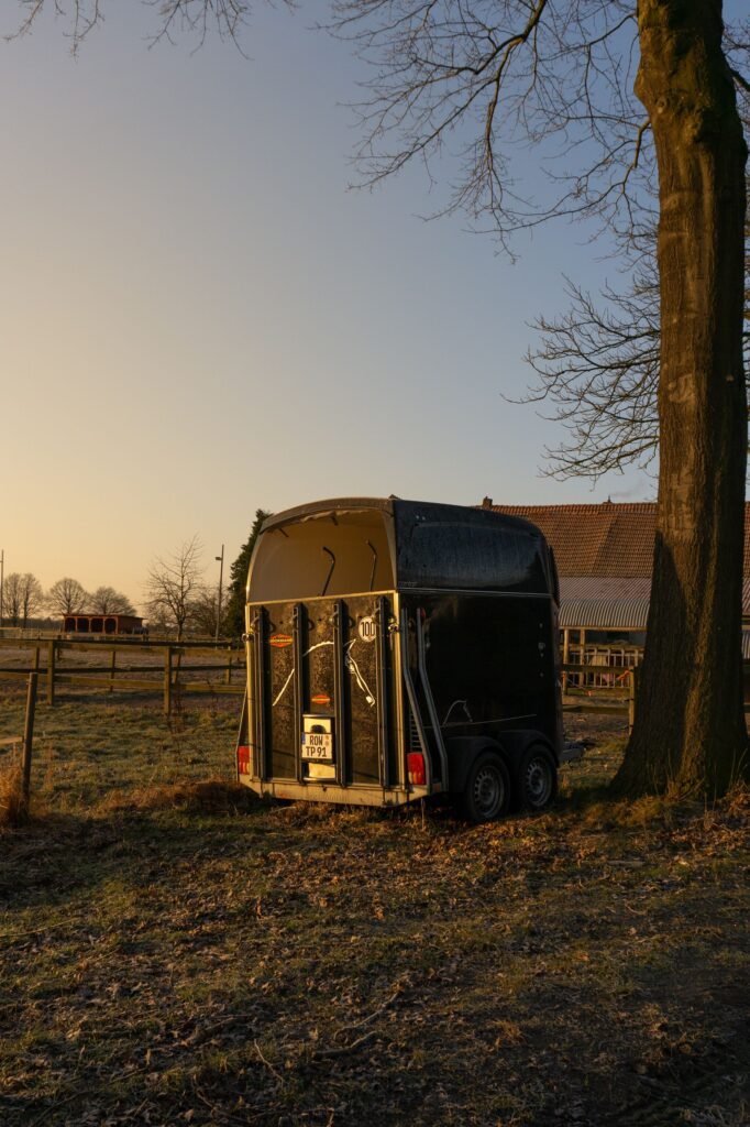 Horse trailer parked under a tree in the countryside
